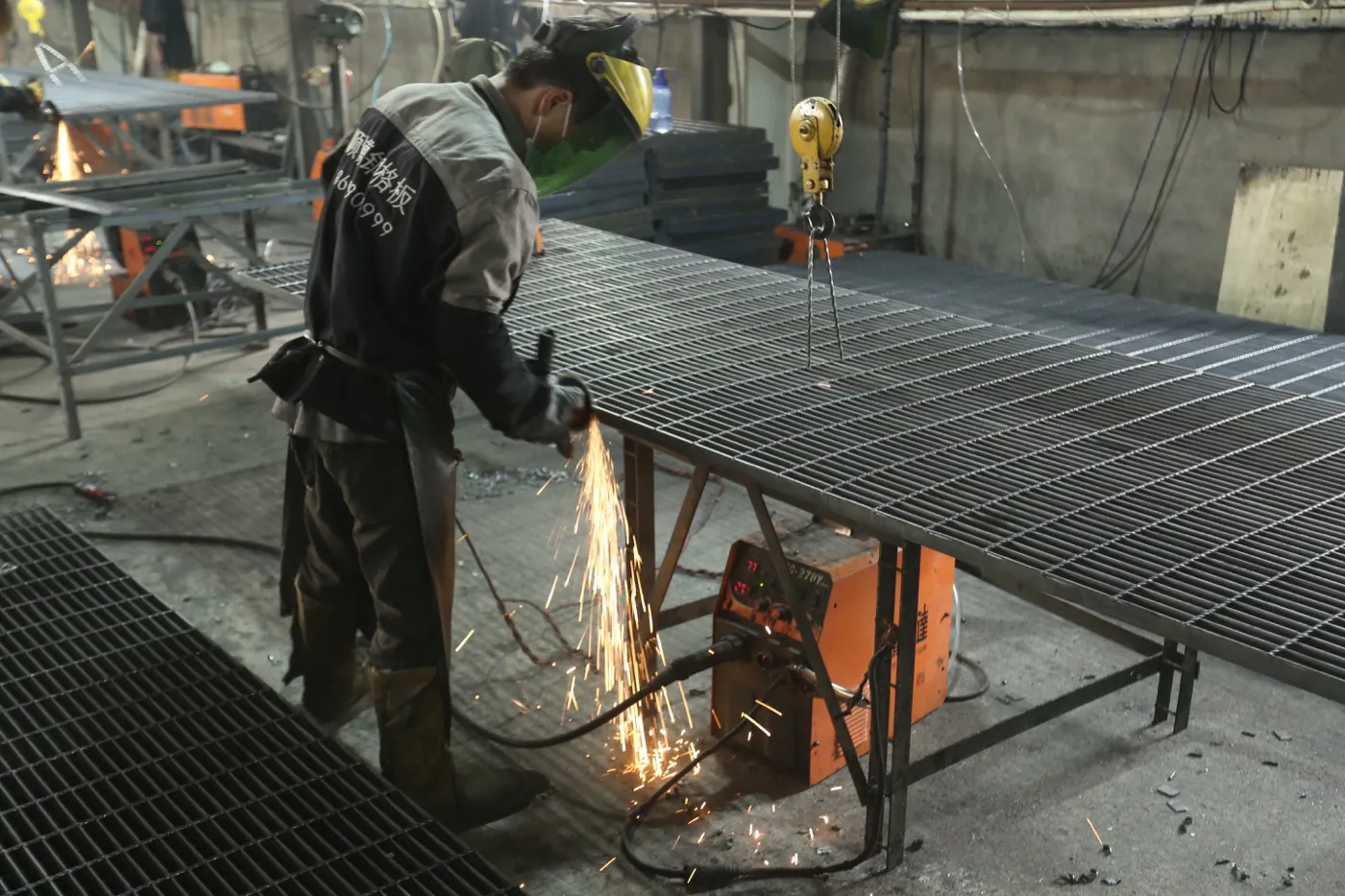 Worker grinding the edge of a fabricated steel grating panel