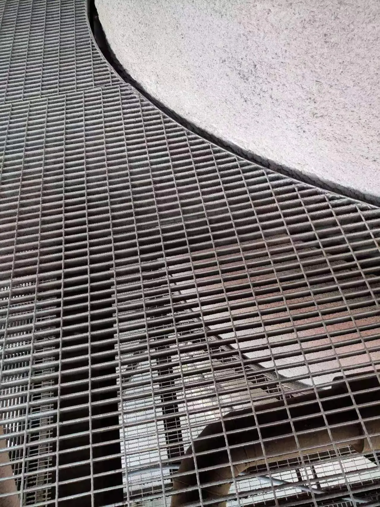Curved steel grating panels fitted around a large process vessel
