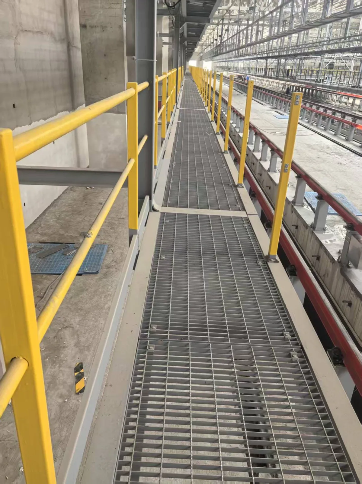 Steel grating access walkway running along an industrial pipe rack