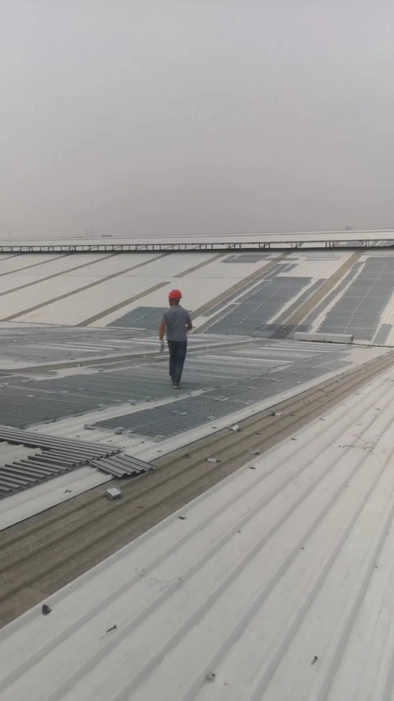 Worker using a steel grating access walkway between solar panels