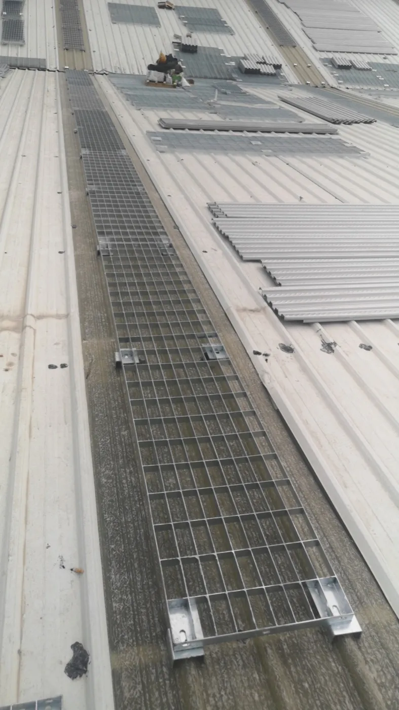 Installation detail of a steel grating walkway beside rooftop solar panels
