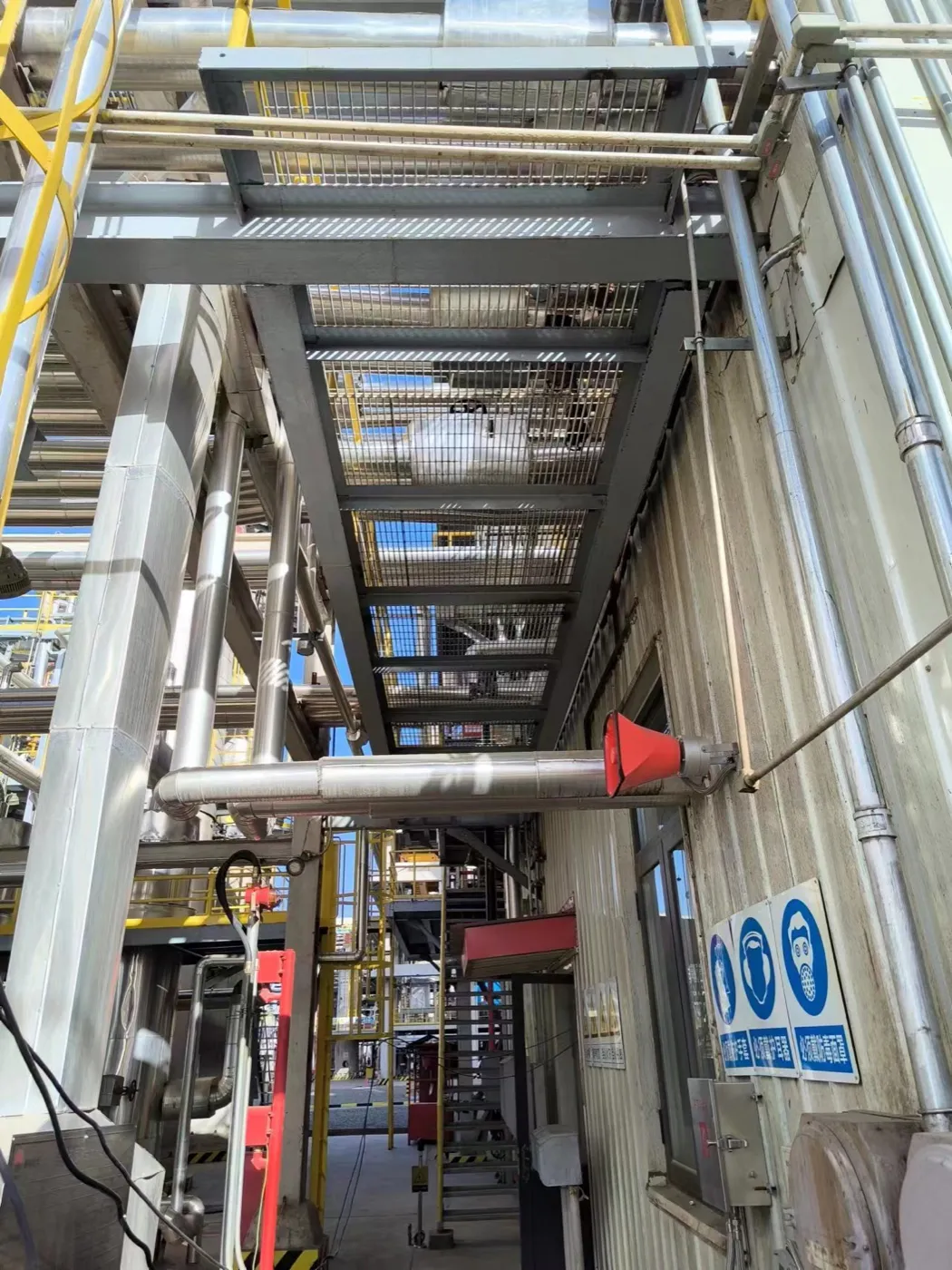 Elevated steel grating maintenance platform above pipe equipment
