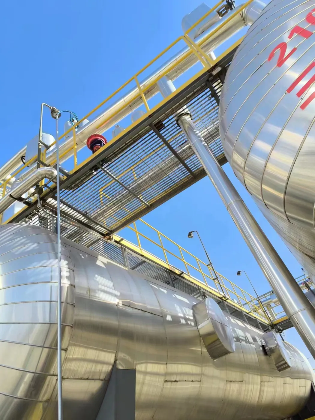 Steel grating maintenance walkway connecting industrial tanks