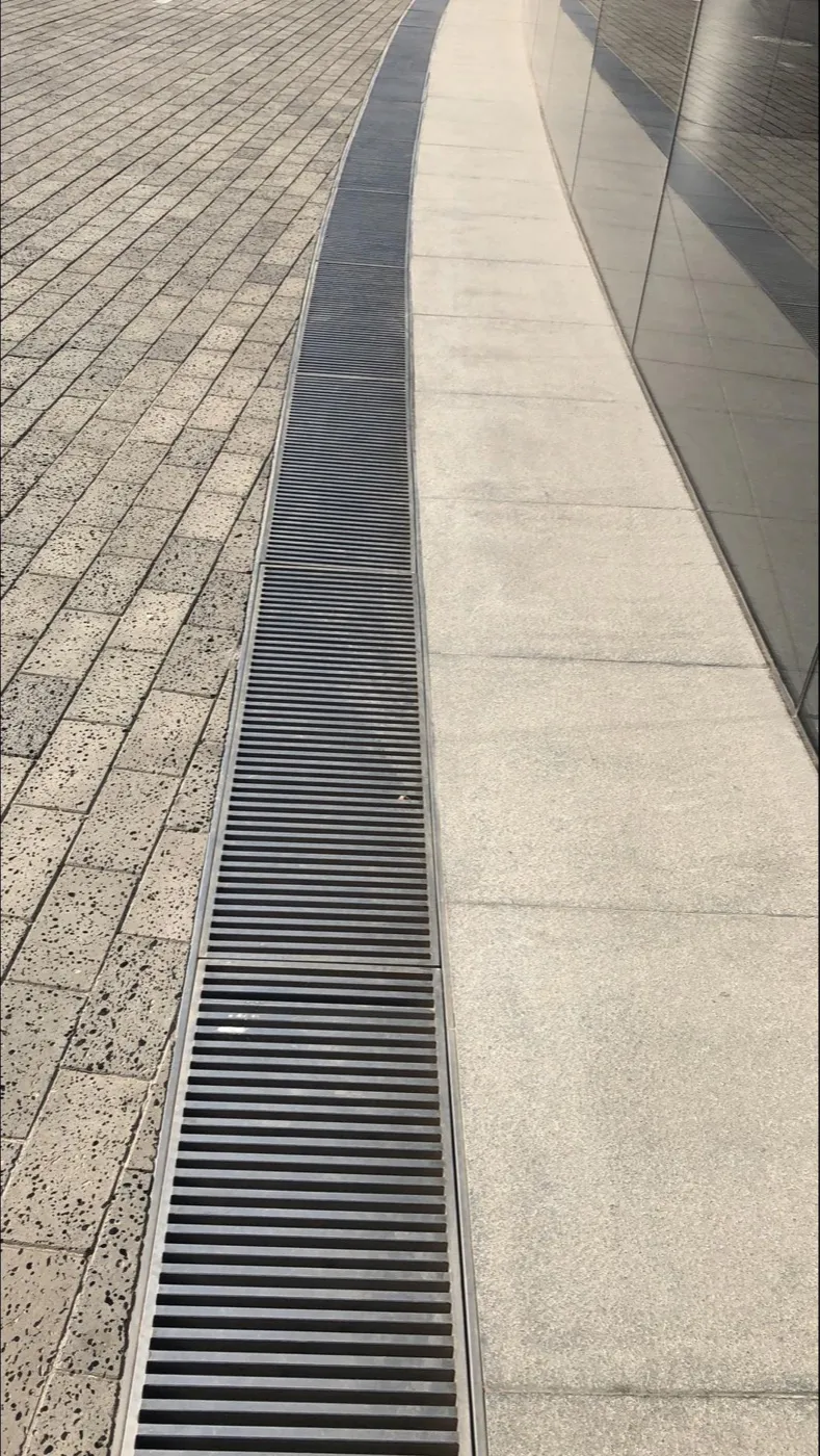 Linear drainage grating integrated into a commercial pedestrian area