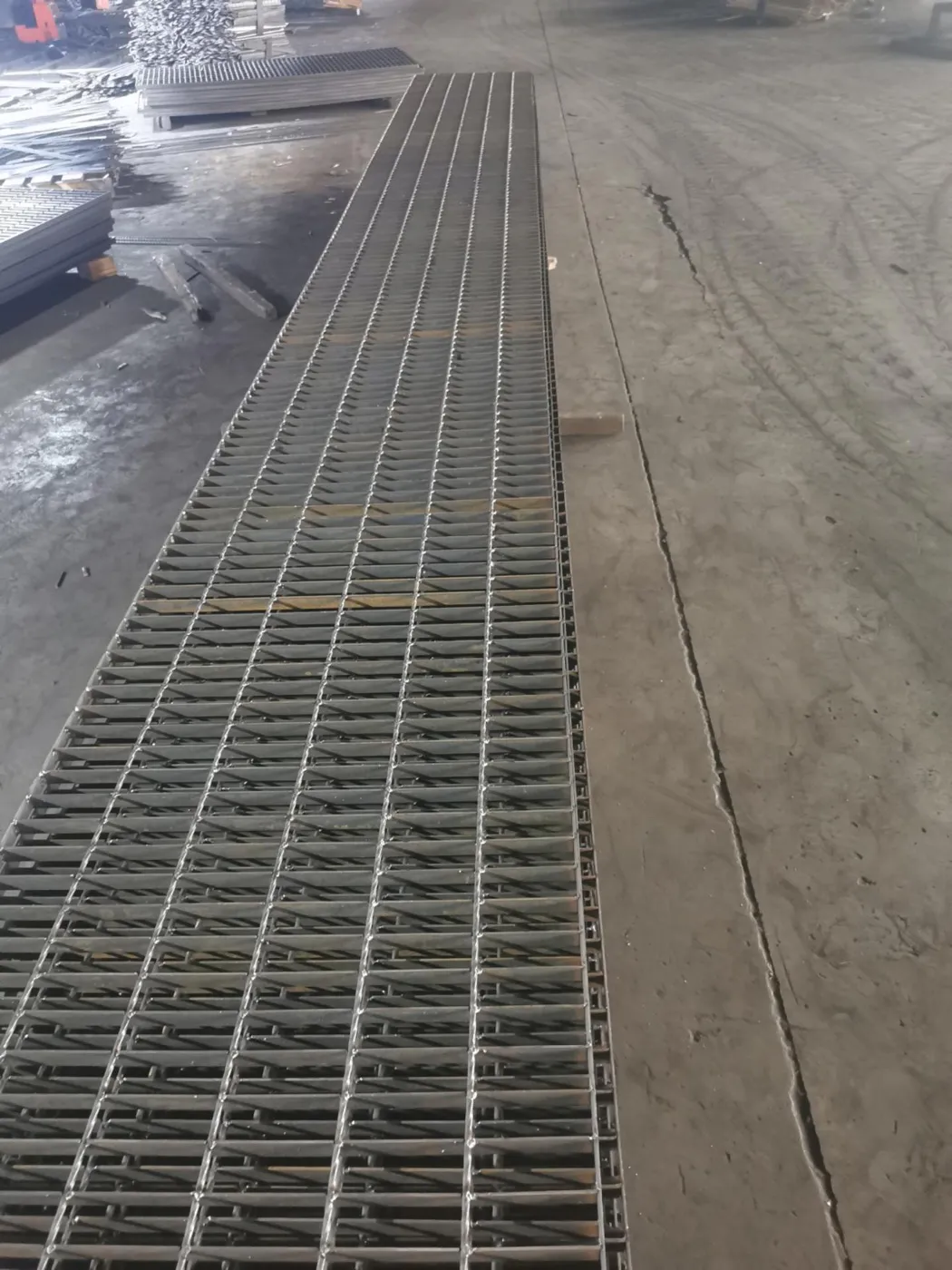 Close view of a steel grating drain cover beside an industrial road