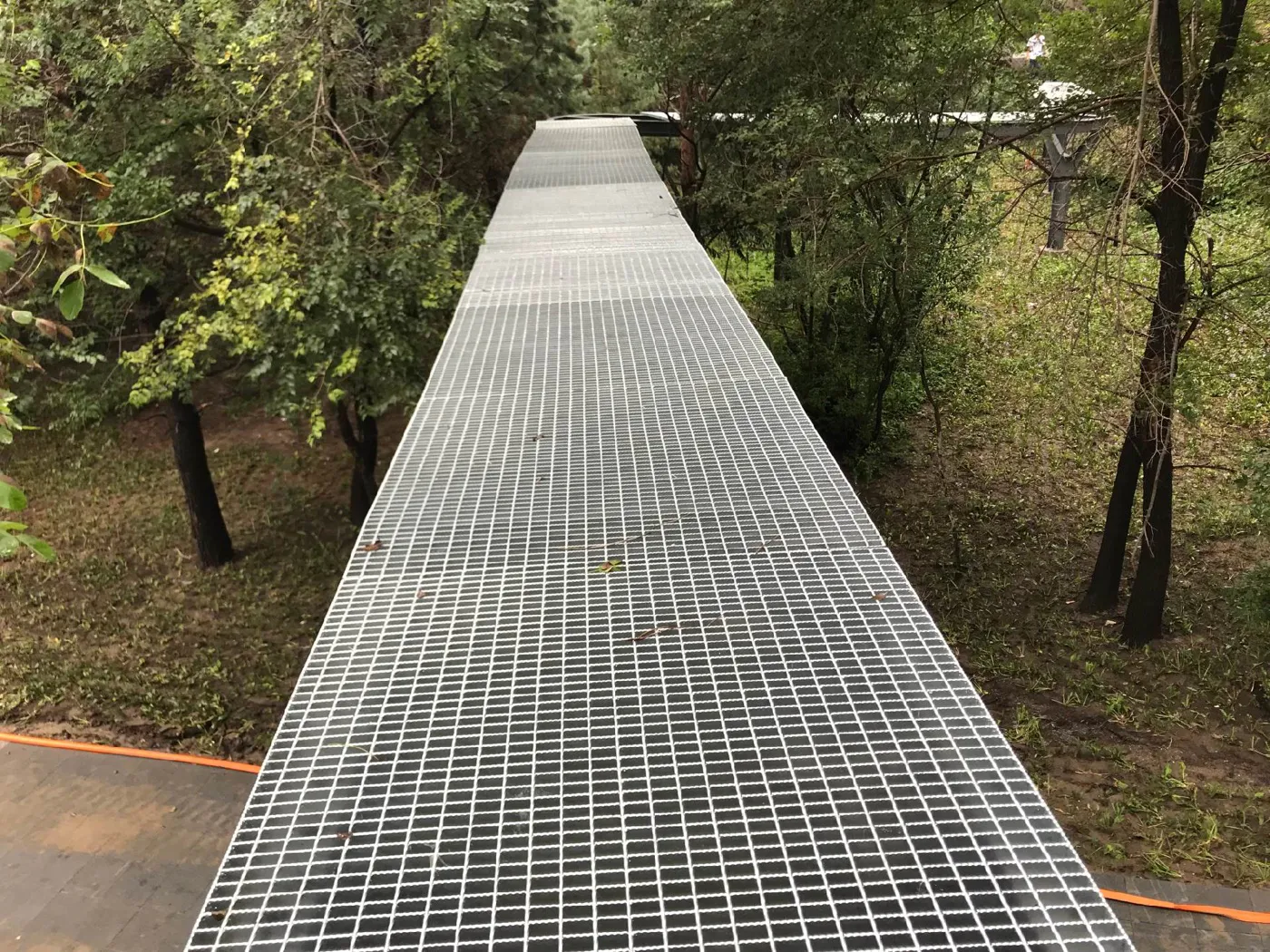 Elevated steel grating boardwalk through a landscaped area