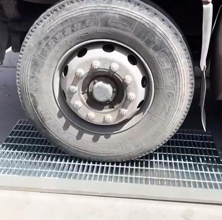 Vehicle tire crossing heavy-duty steel grating industrial flooring
