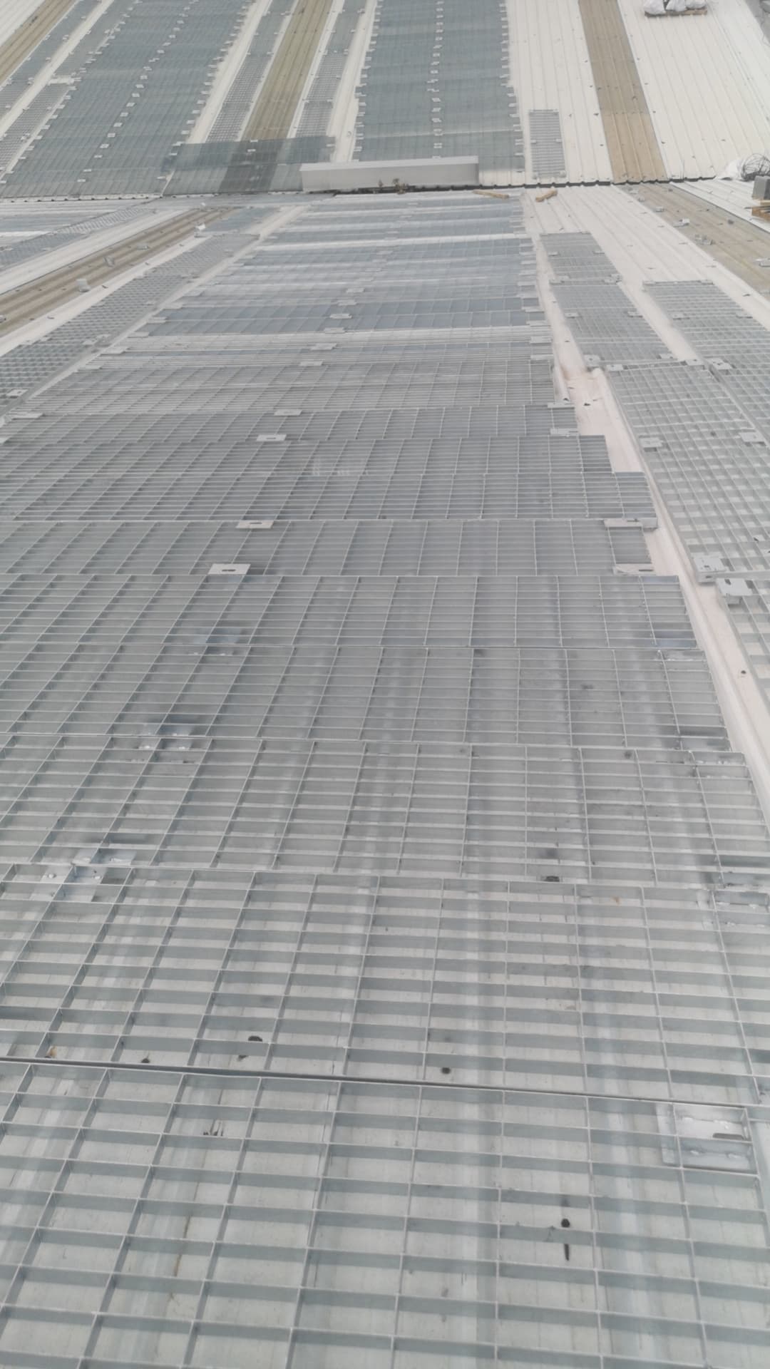 Galvanized grating walkway sections laid across a photovoltaic roof