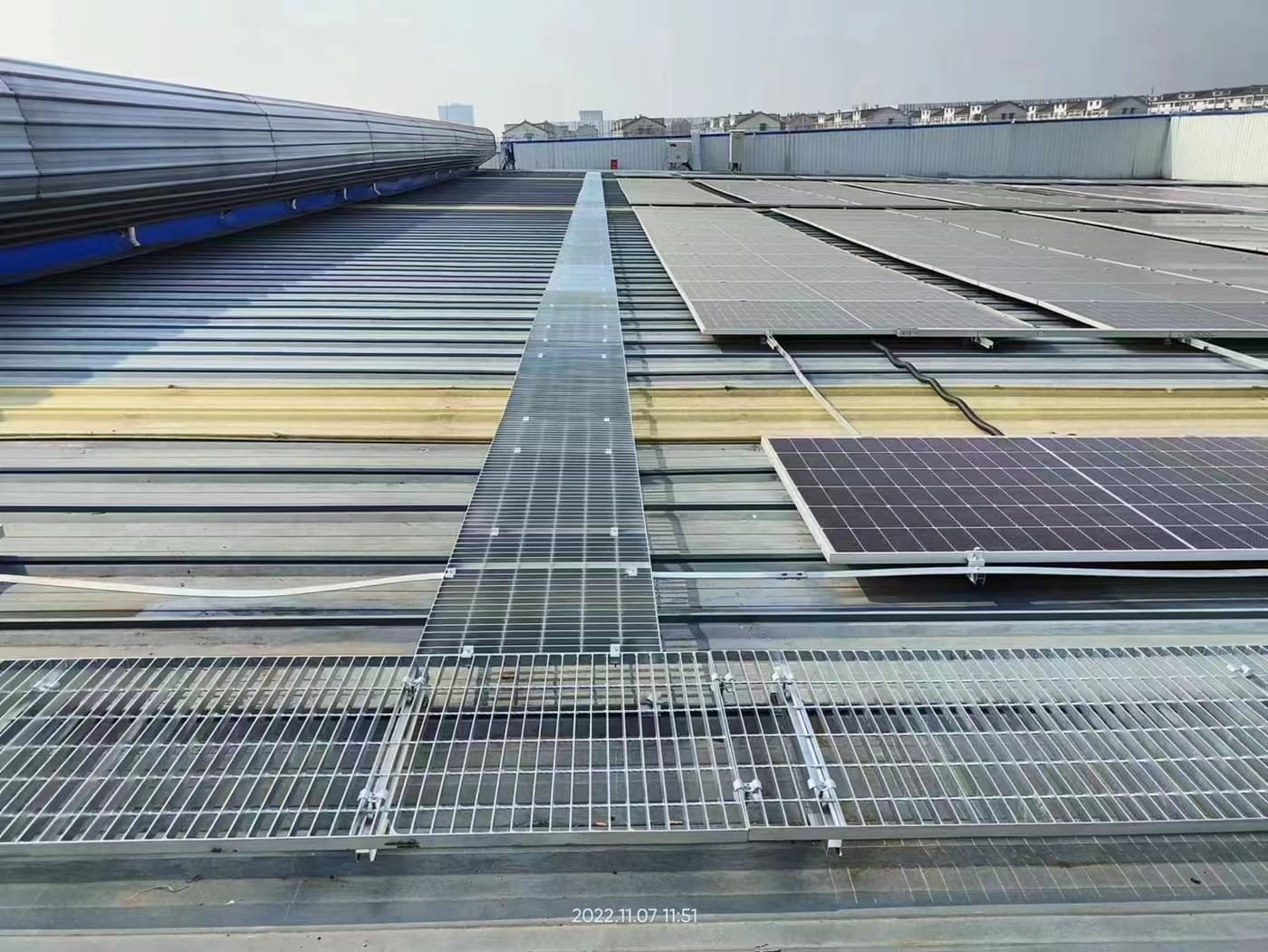 Long grating access walkway running between rooftop photovoltaic arrays