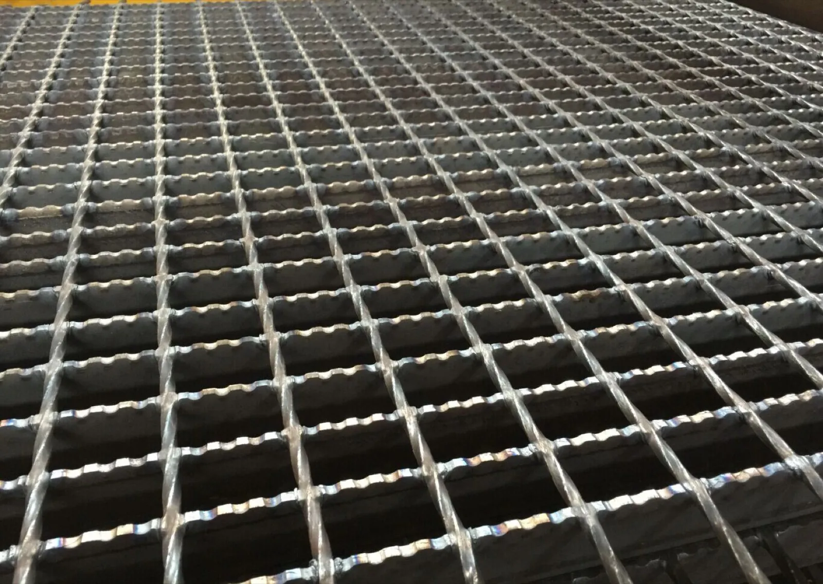 Serrated steel grating with visible notches along the bearing bar tops