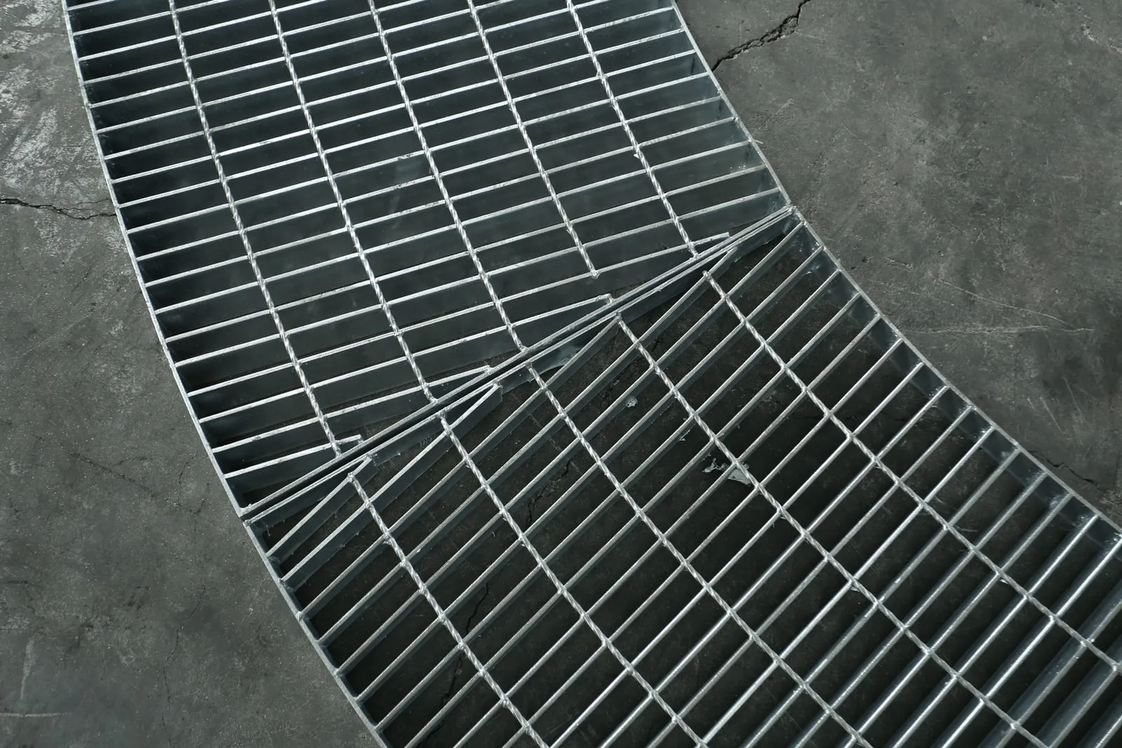 Close workshop view of two fan-shaped steel grating panels meeting at a radial joint