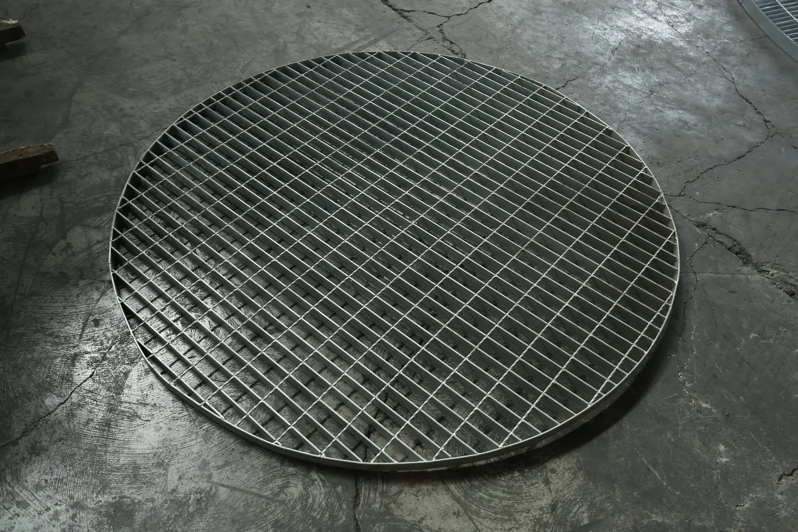 Round custom steel grating panel with a banded circular edge on a workshop floor