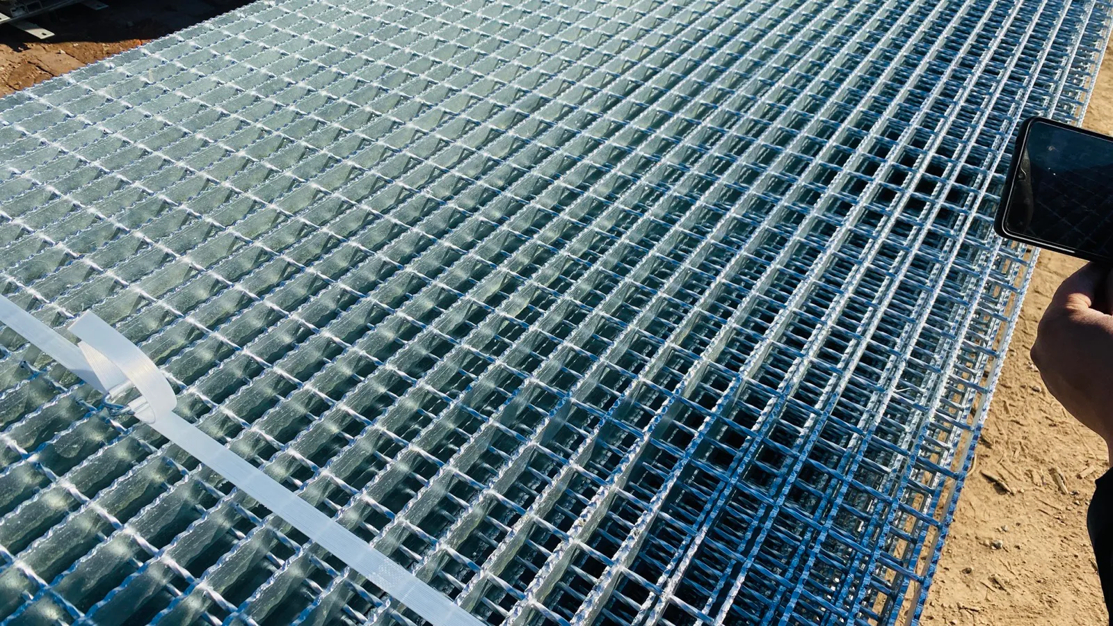 Bundled hot-dip galvanized serrated steel grating panels secured for handling