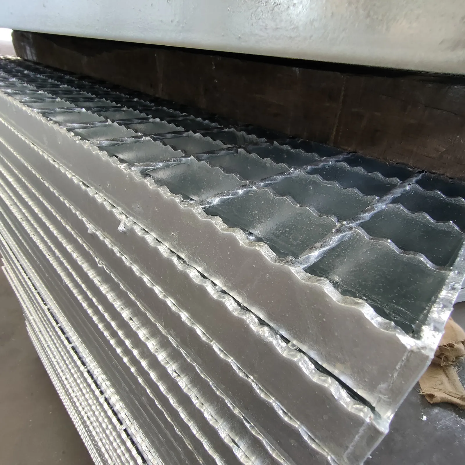 Side view of stacked galvanized grating panels showing repeating serrated bearing bar edges