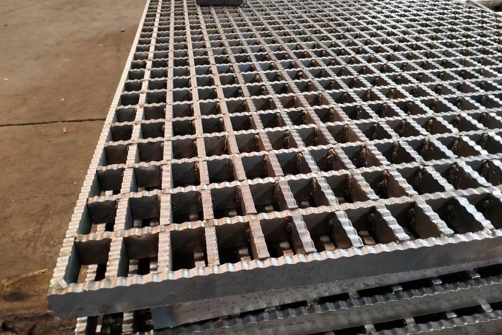 Fabricated serrated steel grating panels with welded intersections and banded edges