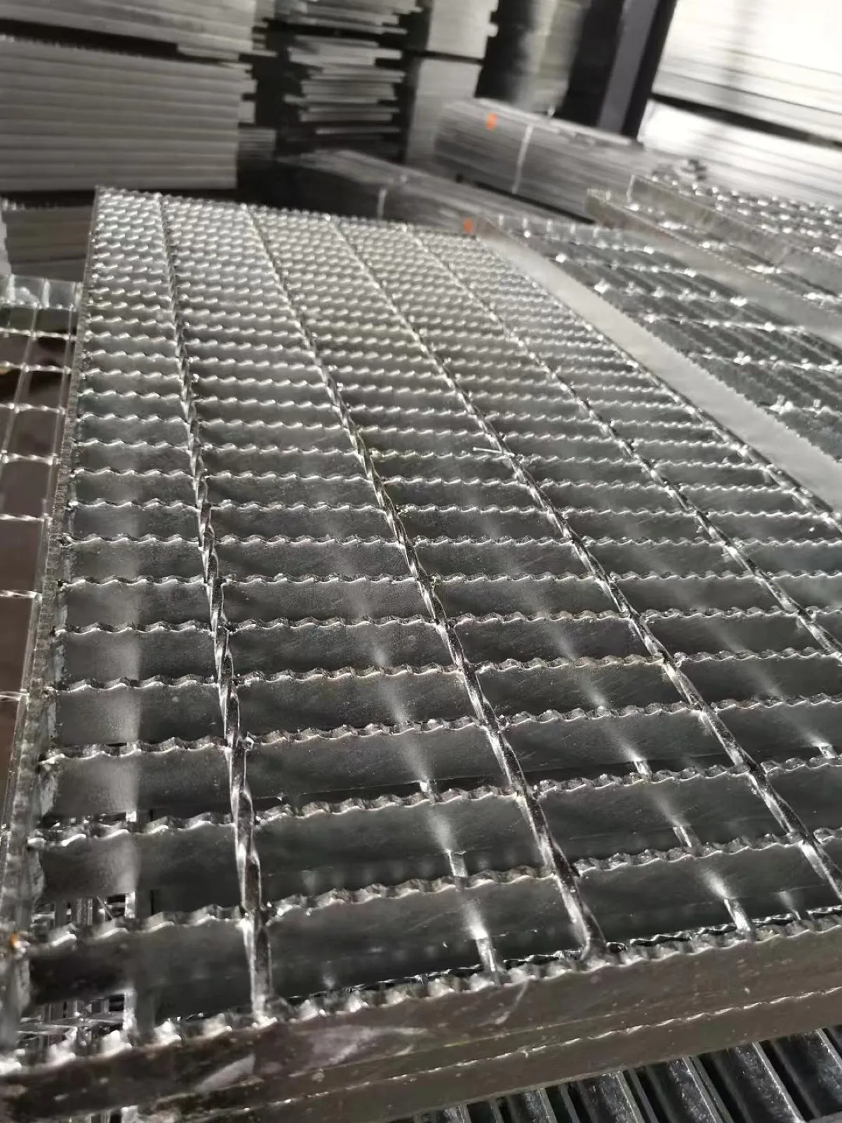 Galvanized serrated steel grating panel in a workshop with toothed bearing bars
