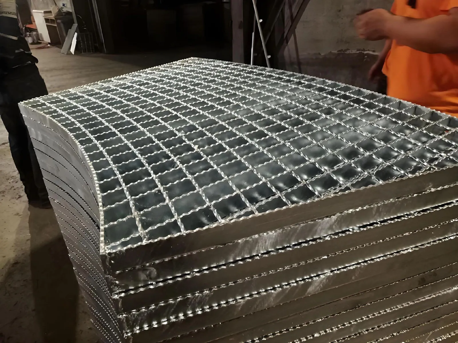 Stacked galvanized serrated steel grating panels during workshop handling