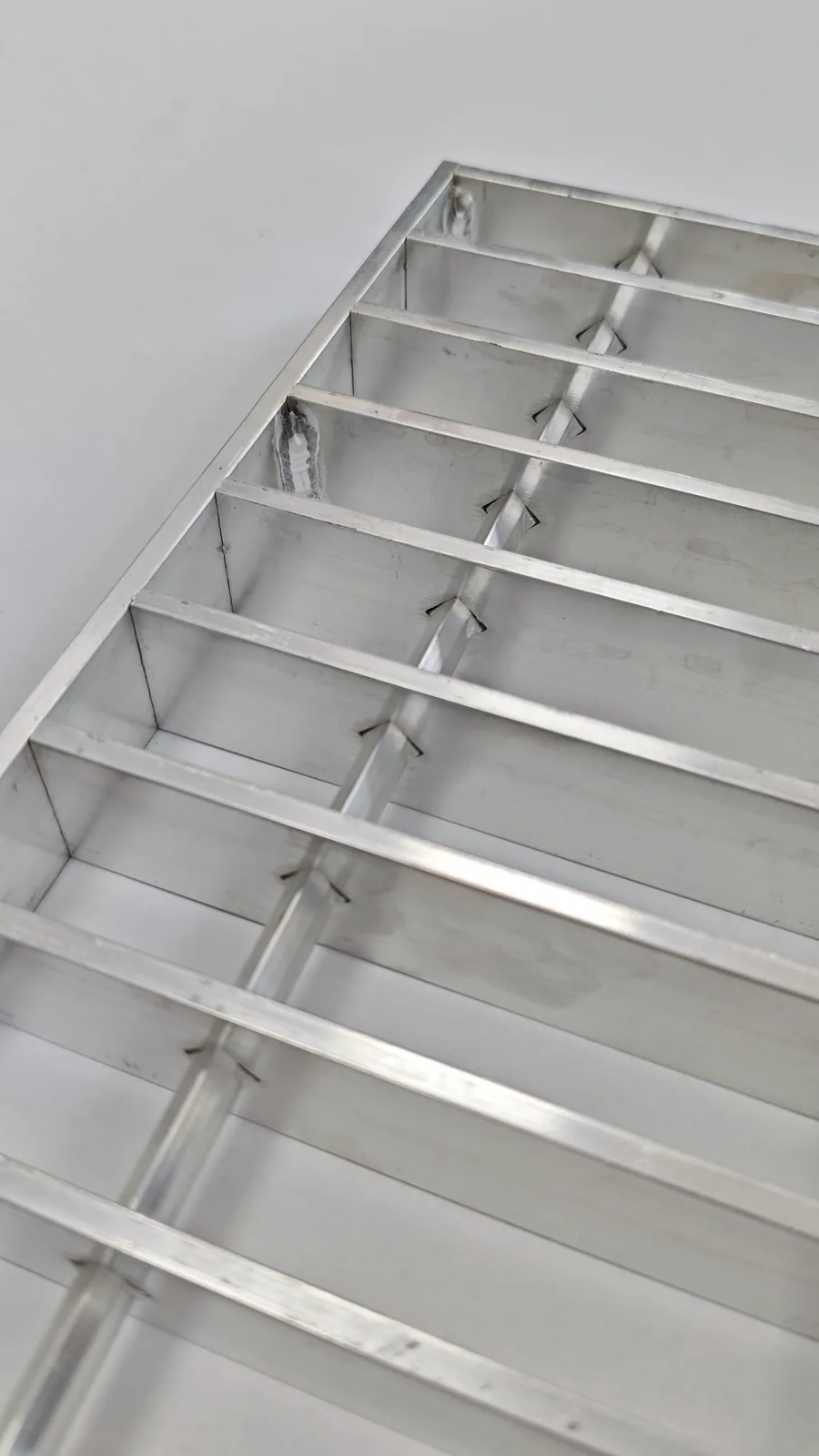Underside of an aluminum swage-locked grating sample showing deformed cross-bar locking points