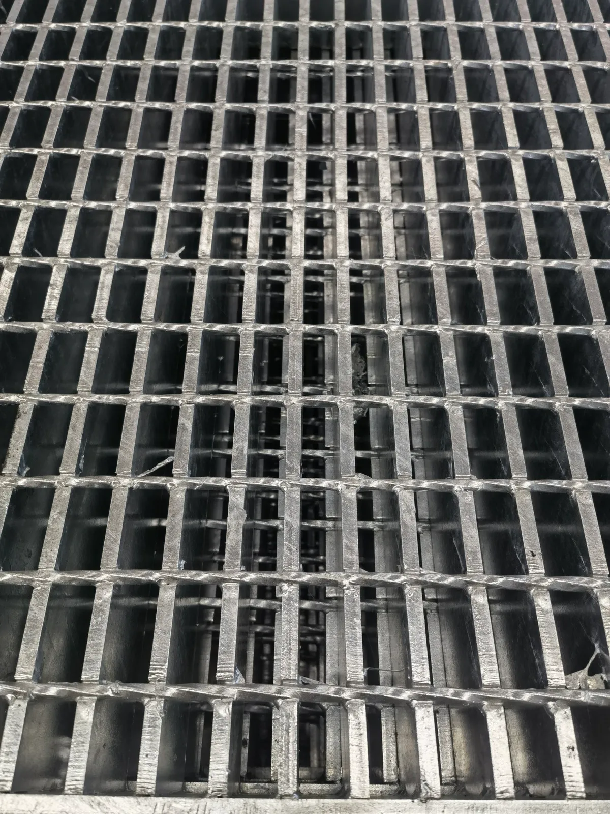 Close-up of stacked welded steel grating panels viewed along the bearing bars