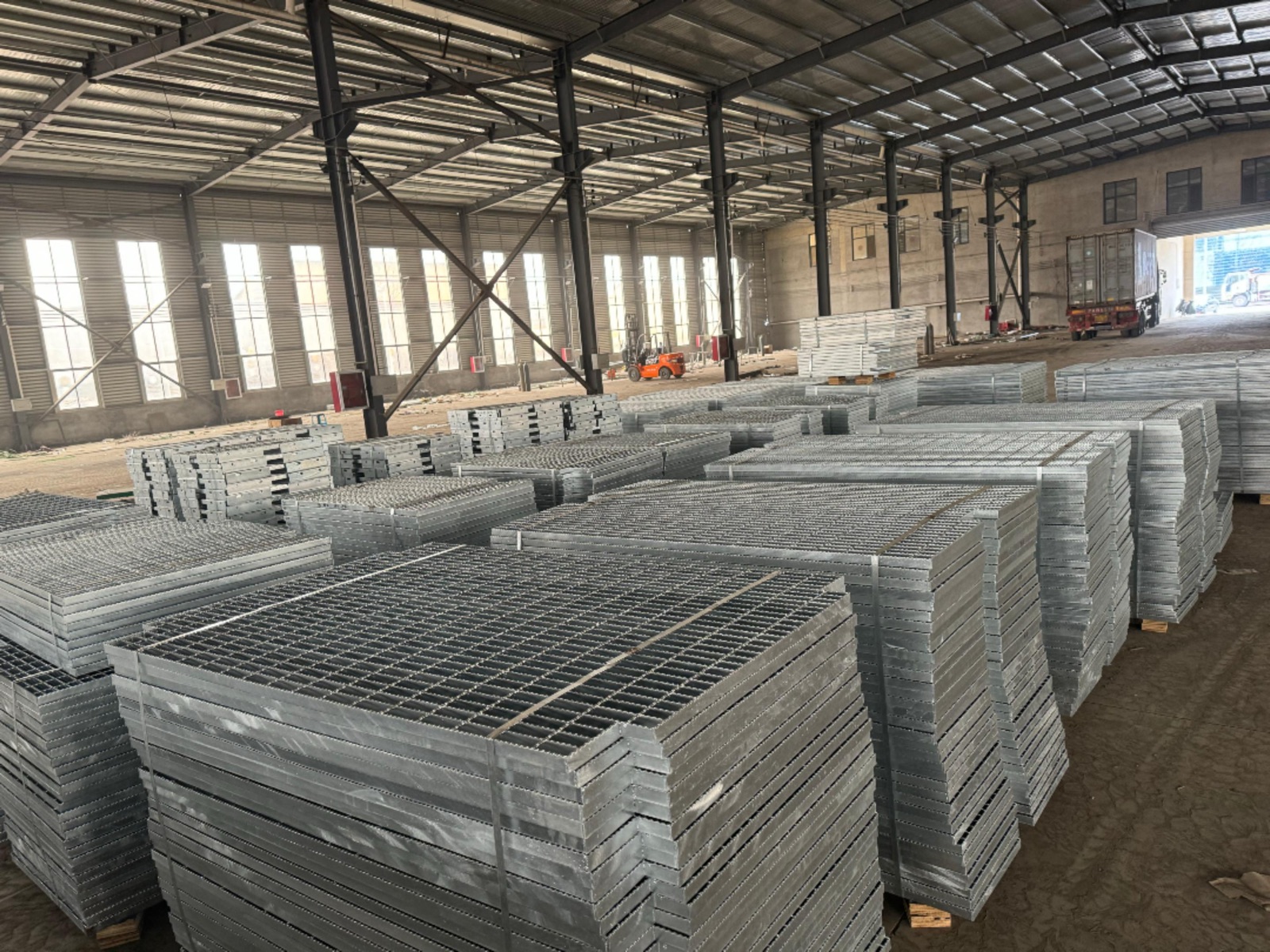 Stacked serrated steel grating panels in a bright warehouse