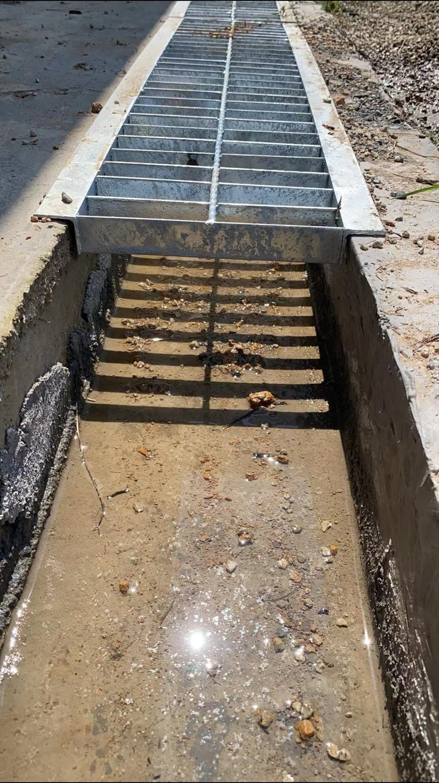 Grating cover seated over an open drainage trench