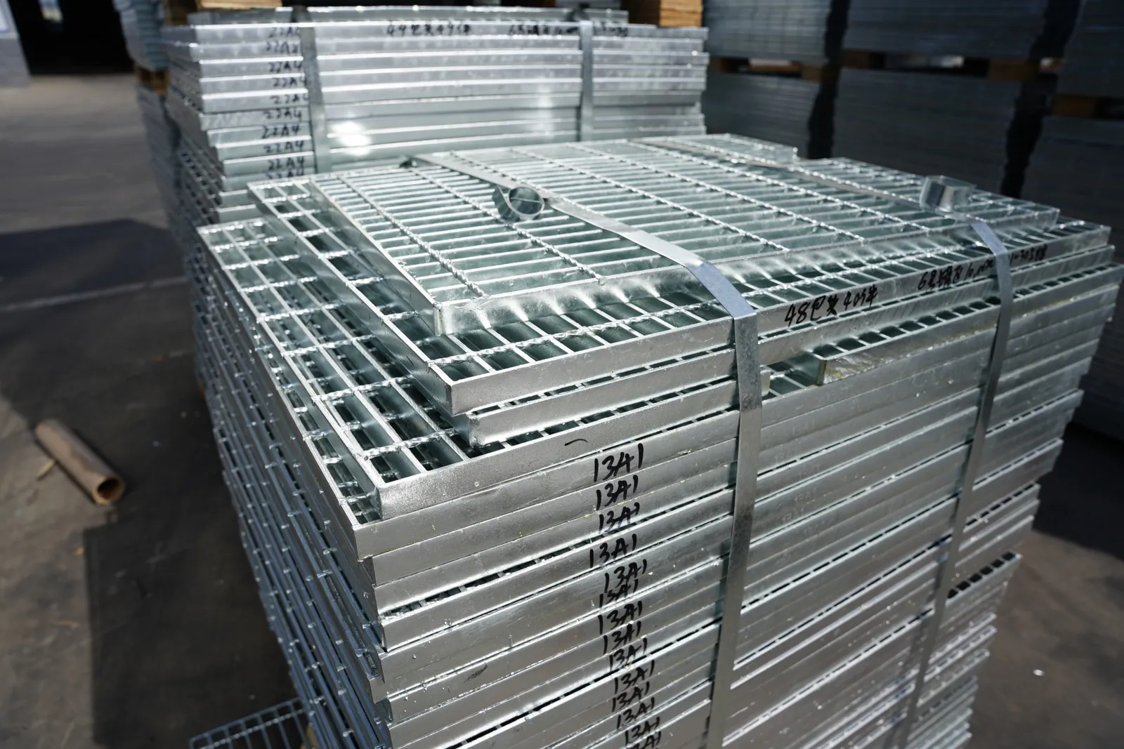 Numbered hot-dip galvanized steel grating panels stacked and strapped in the workshop