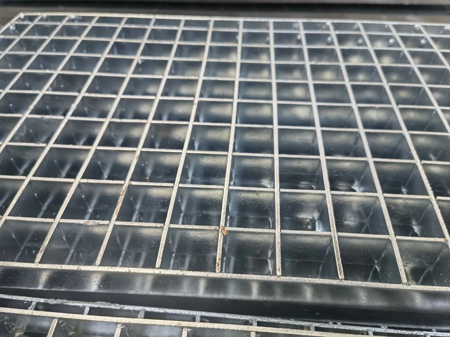 Press-locked steel grating panel showing the regular square grid