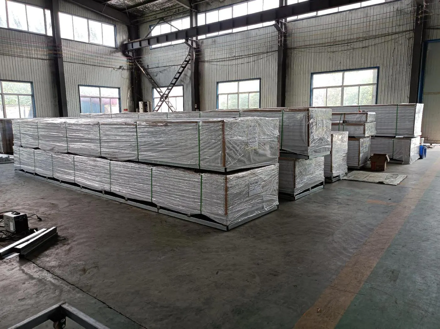 Wrapped grating panel bundles supported on steel bases inside the workshop