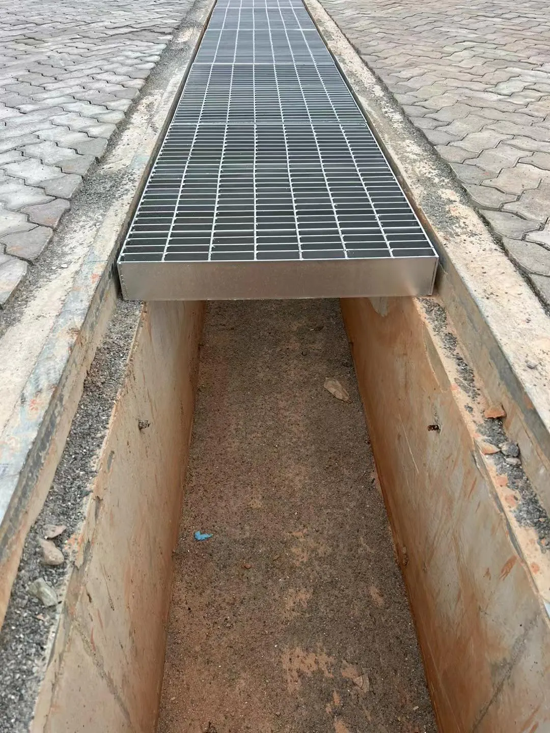 Close-up of a framed trench cover grating seated over an open drainage channel