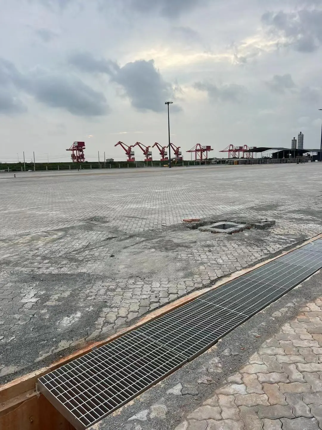Long galvanized trench cover grating installation beside an industrial yard