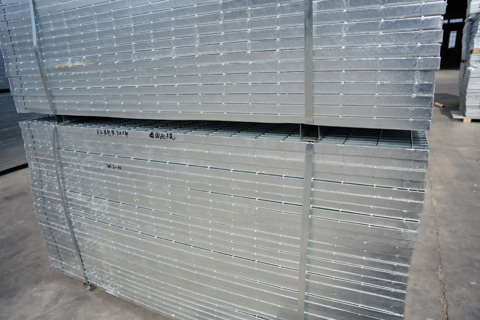 Close view of strapped galvanized steel grating bundles with panel markings