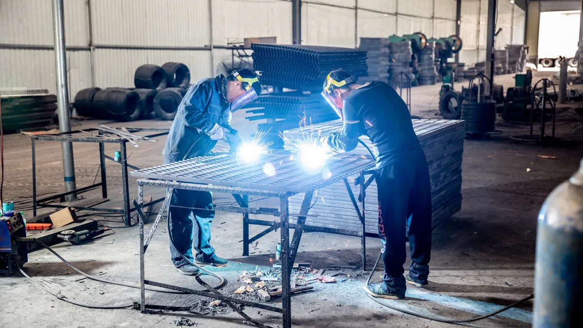 Workers manually welding custom steel grating panels