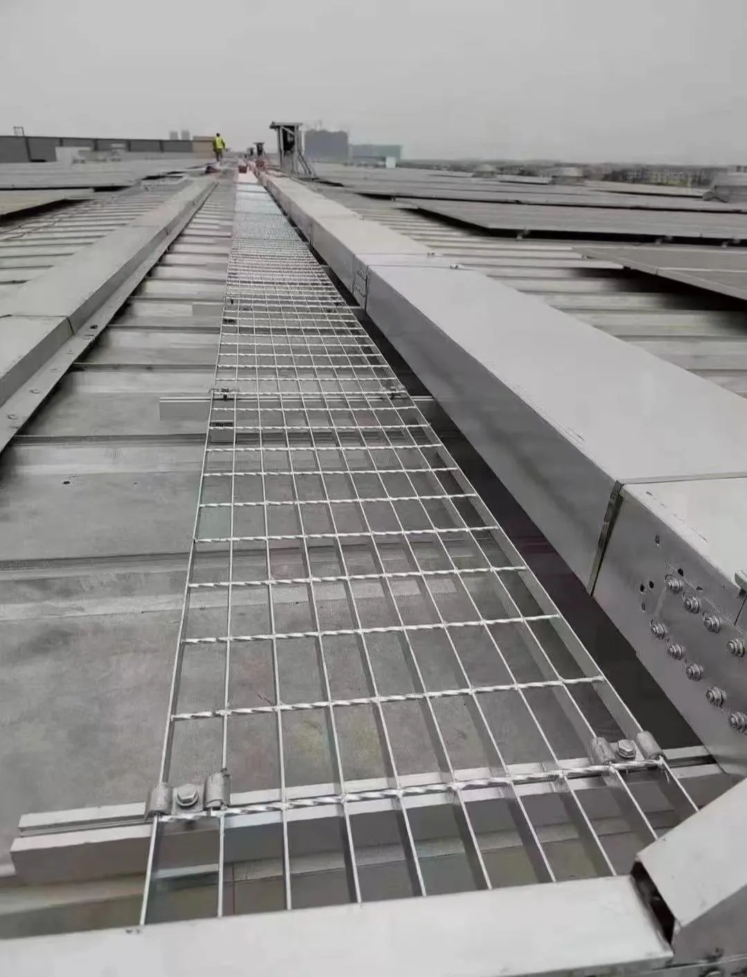 Steel grating inspection walkway between commercial rooftop solar arrays