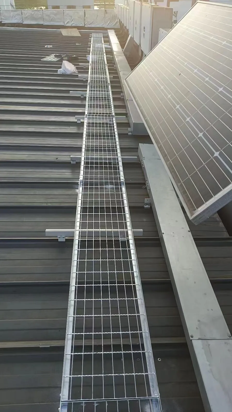Steel grating maintenance walkway beside rooftop photovoltaic panels