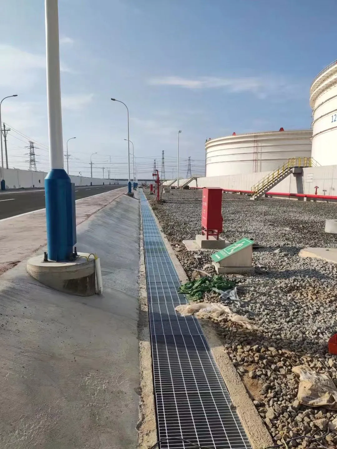 Long steel grating drainage channel beside the tank-farm road