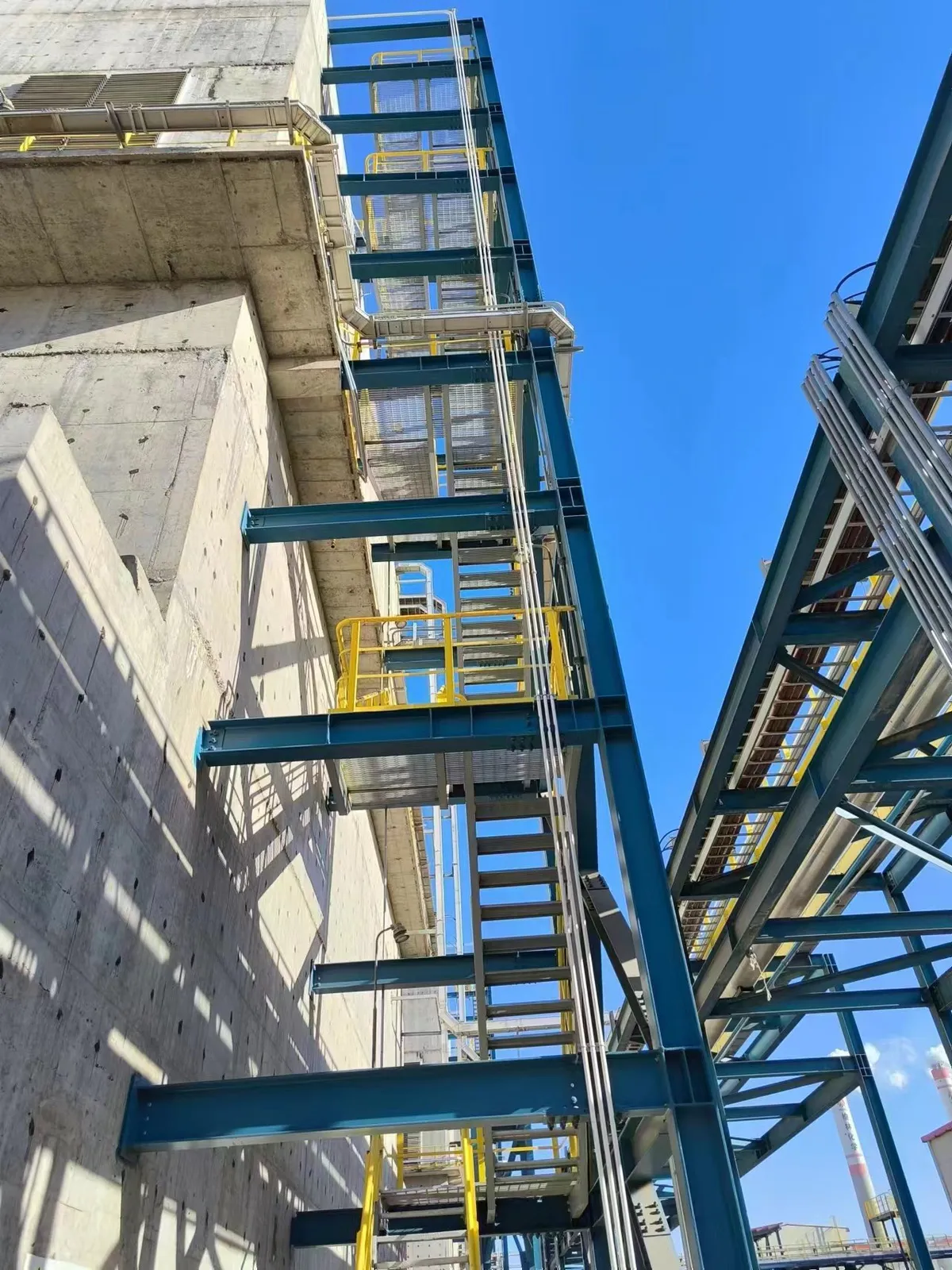 Vertical steel grating access platforms beside a process pipe rack
